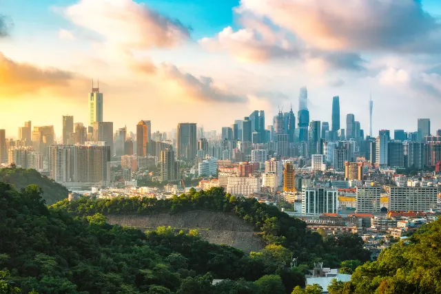 Guangzhou skyline seen from the forested slopes of Baiyun Mountain at sunrise