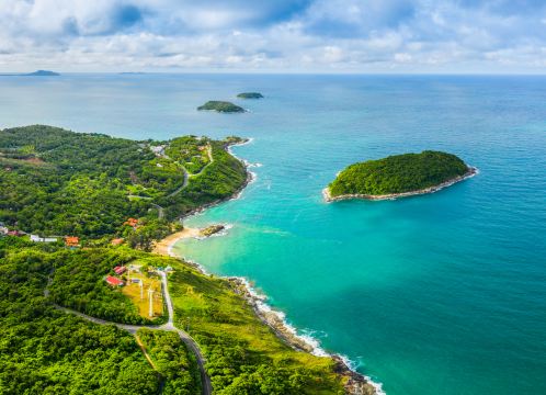 Aerial view of a green Phuket headland meeting turquoise water, with small islands offshore