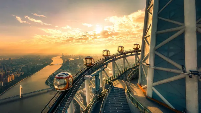 Bubble tram cabins circling the Canton Tower at sunset above the Guangzhou skyline and the Pearl River