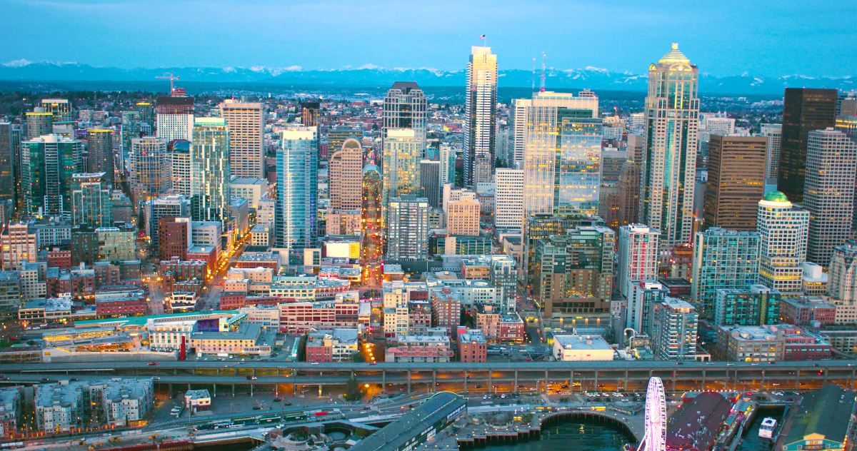 Aerial view of downtown Seattle at dusk with the stadium district and waterfront in the foreground and the skyline behind