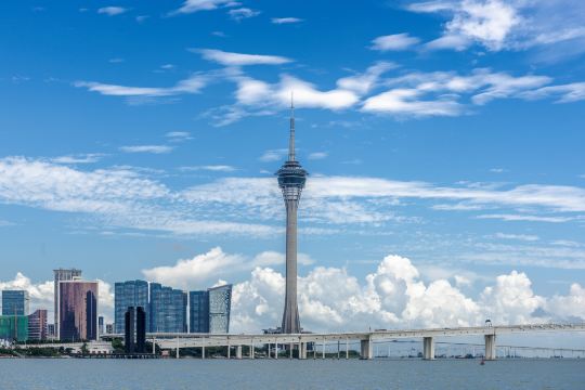 The Macau Tower standing above the Sai Van bridge and the waterfront, with the peninsula's towers on the left