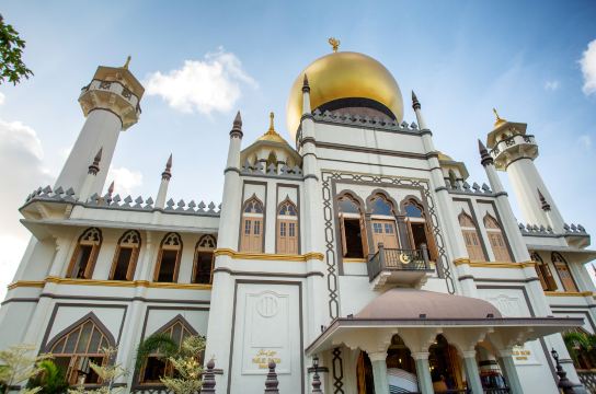 The white facade and gold dome of Sultan Mosque in Kampong Glam, Singapore, against a blue sky