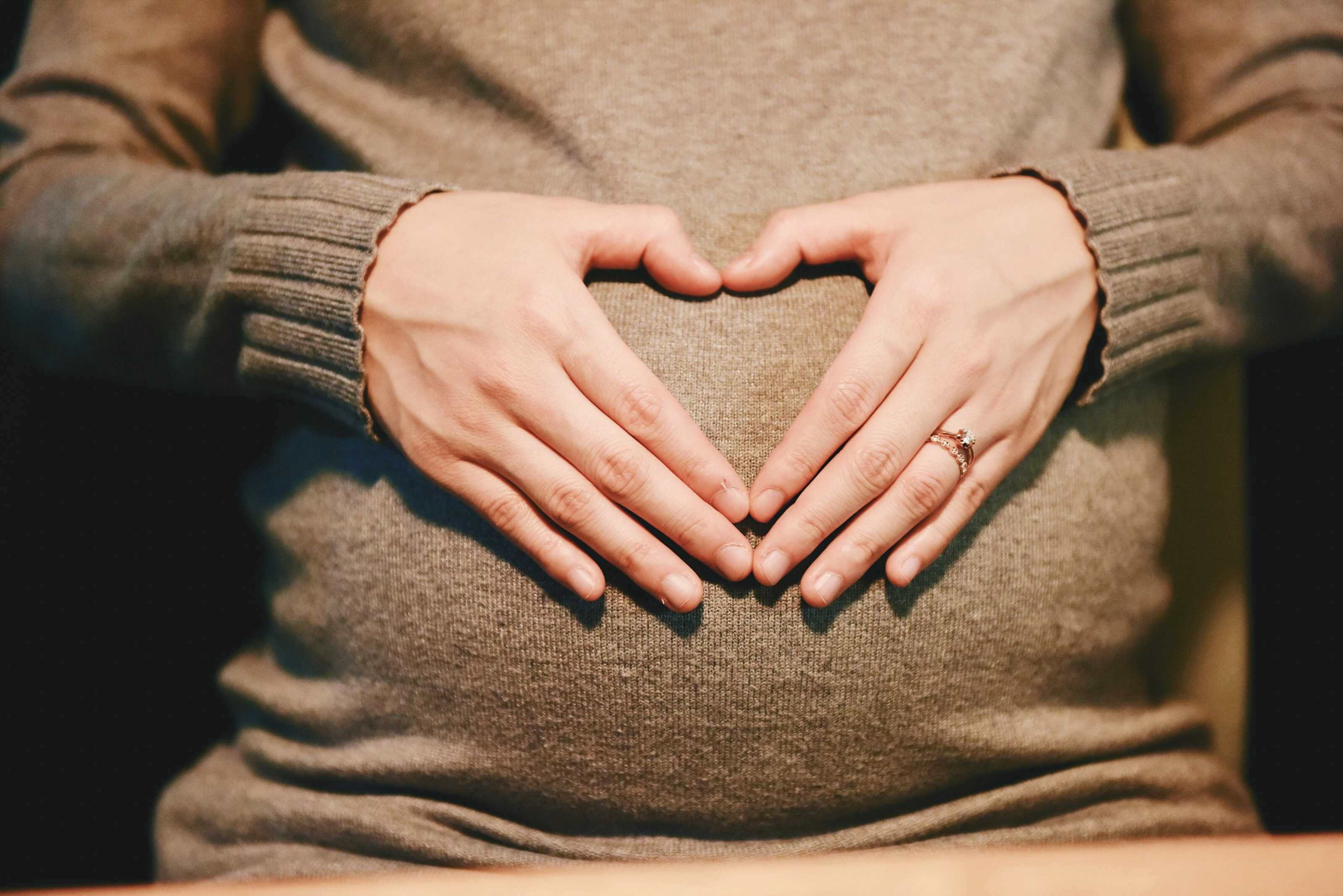pregnant woman with heart-shaped hands