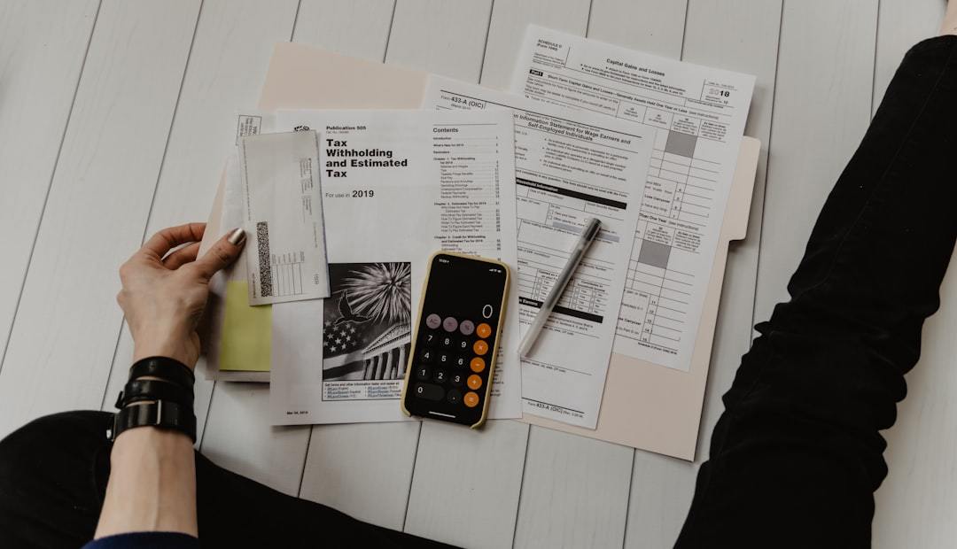 person holding paper near pen and calculator Via Unsplash (by Kelly Sikkema)