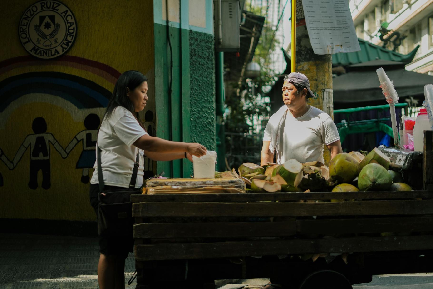 Woman buying fresh coconuts from a street vendor in Manila
