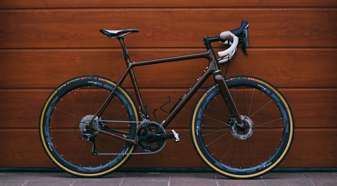 black road bike against wooden wall Via Unsplash (by Dmitrii Vaccinium)