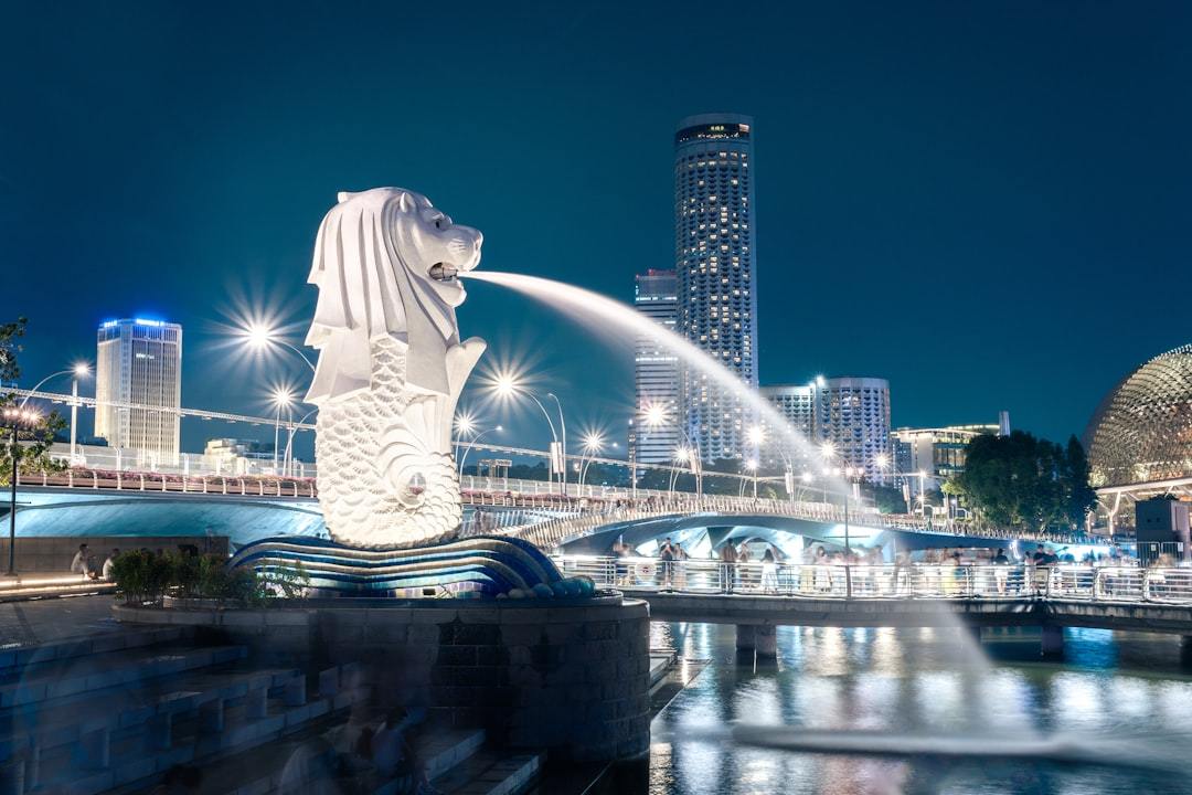 Merlion statue spouting water in singapore at night Via Unsplash (by Jayjayli)