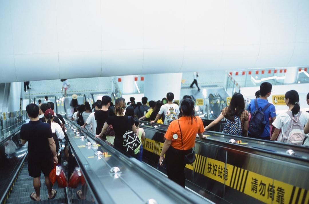 A group of people riding on an escalator Via Unsplash (by Quan Jing)