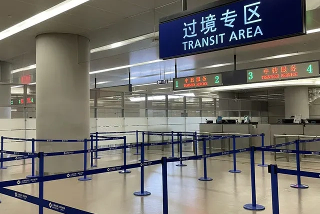 上海浦東国際空港のトランジット専用エリア。青い案内ロープと「TRANSIT AREA」と書かれた標識が見える乗り継ぎ手続きカウンターの様子。