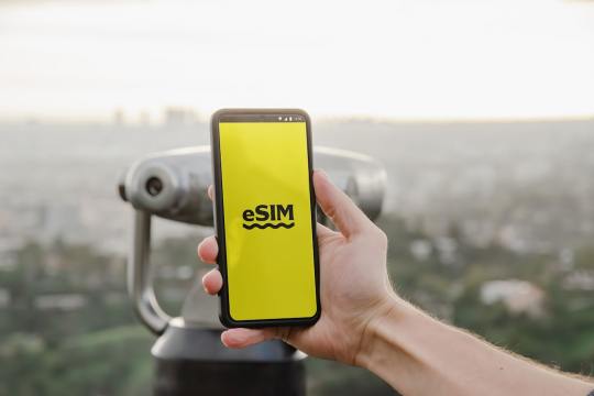 a person holding up a cell phone with a logo on it Via Unsplash (by Opal Pierce)