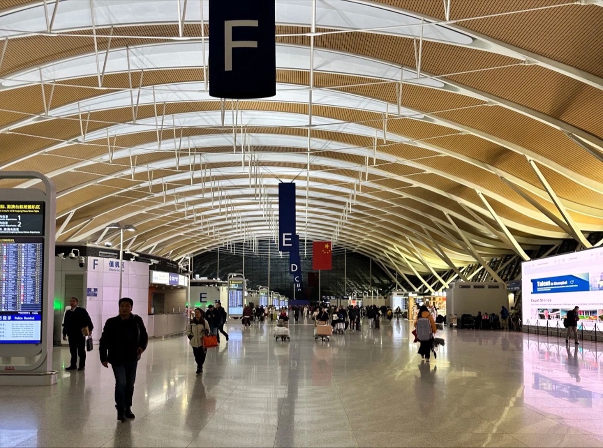 上海浦東国際空港の出発ロビー。E・Fカウンター付近の広々とした空間に多くの乗客が並び、チェックインや搭乗手続きを行っている様子。