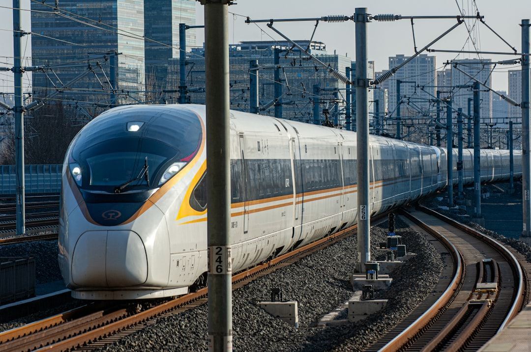 a white and yellow train traveling down train tracks Via Unsplash (by KUA YUE)