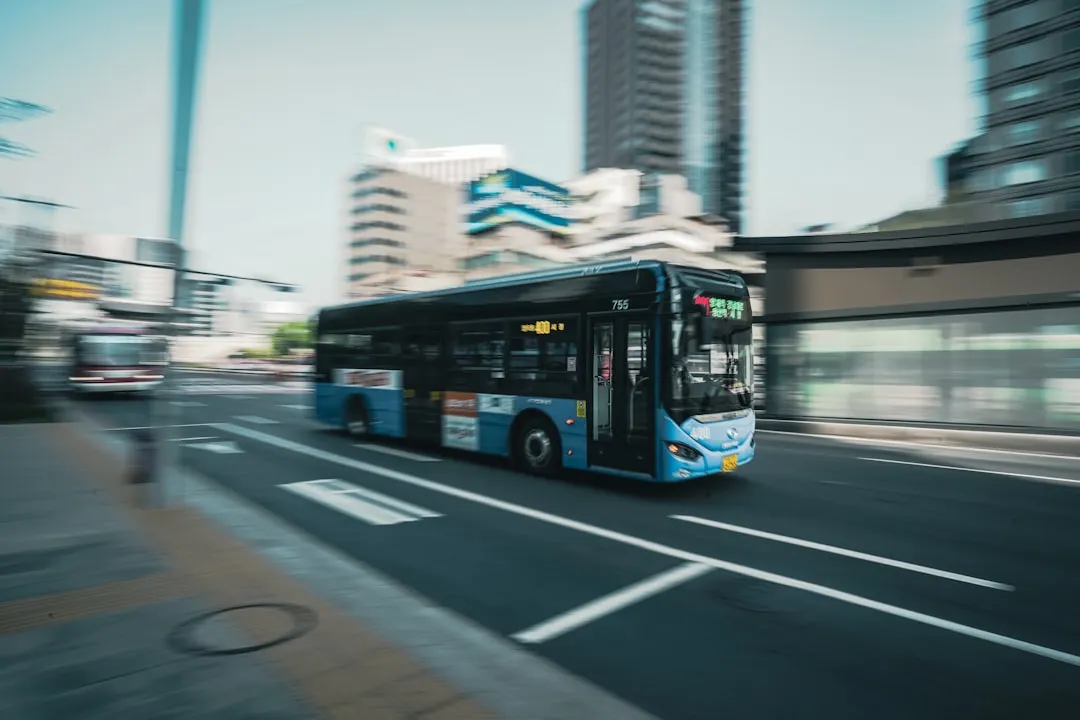 a bus driving down a street Via Unsplash (by Sean Lee)
