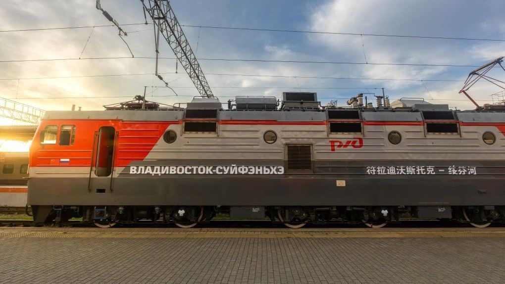 Красно-серый локомотив поезда Владивосток — Суйфэньхэ на станции в лучах заходящего солнца
