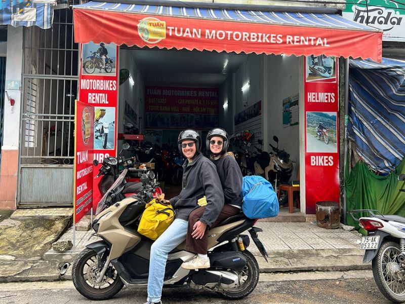 Travelers on a rented scooter outside a motorbike rental shop in Ho Chi Minh City.