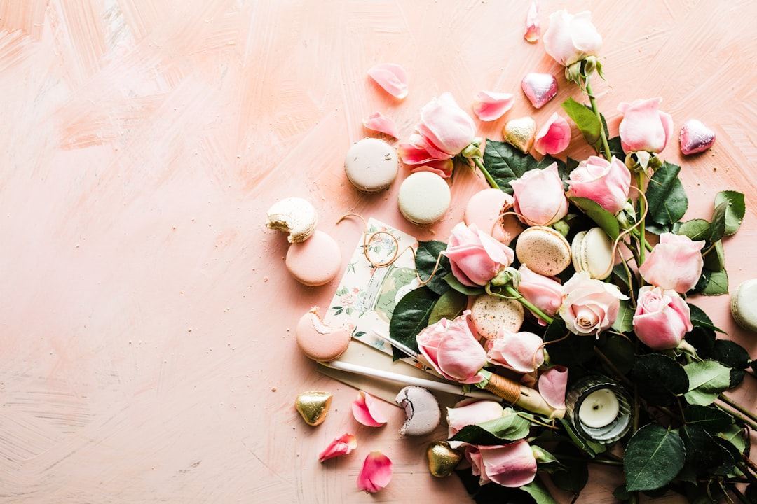 ภาพถ่ายมุมสูงของมาการองและดอกกุหลาบสีชมพู จาก Unsplash (โดย Brooke Lark)