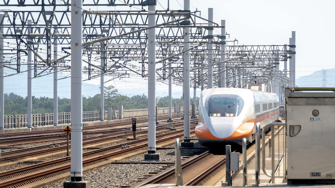 a white and orange train traveling down train tracks Via Unsplash (by Winston Chen)