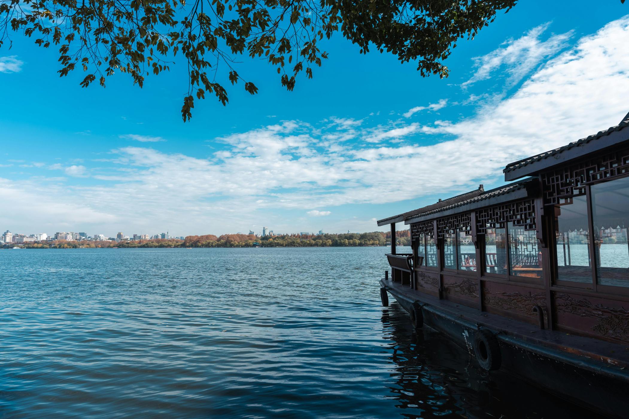 Pemandangan tenang perahu tradisional di Danau Barat di Hangzhou, Cina, di bawah langit biru cerah. Via Pexels (by Acres of Film)