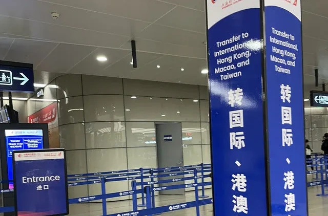 上海浦東国際空港の国際線乗り継ぎエリア入口。青い標識に「Transfer to International, Hong Kong, Macao, and Taiwan」と書かれた案内板が並ぶ。