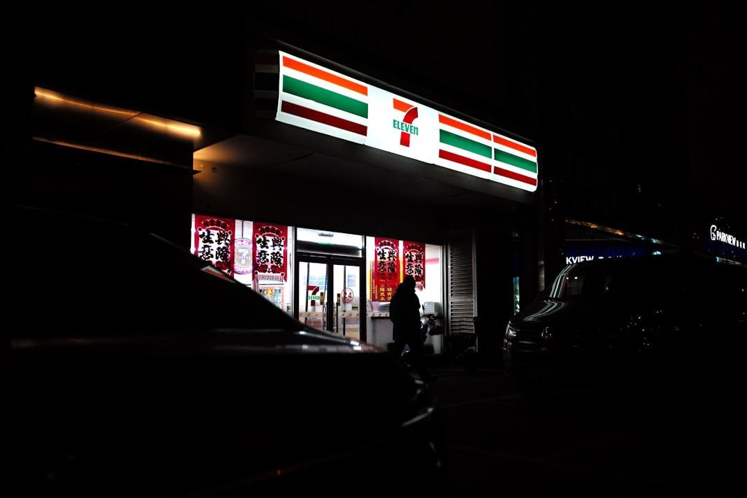 a person standing outside of a building at night Via Unsplash (by Howen)