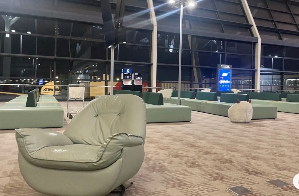 上海浦東国際空港の深夜待合エリア。緑色のソファとリクライニングチェアが並び、夜間便の乗り継ぎ客が静かに過ごせる休憩スペース。