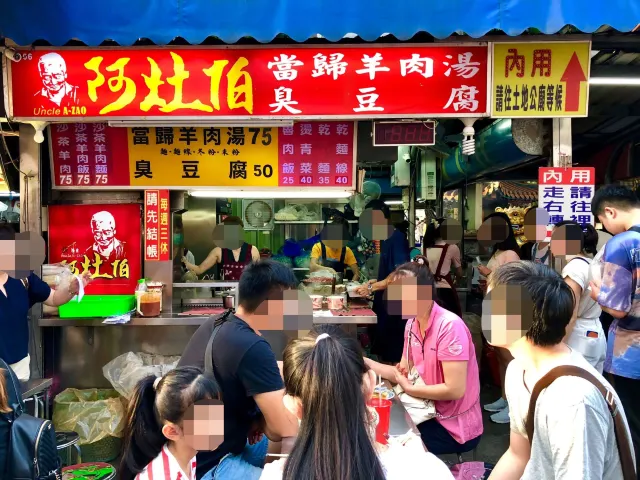 阿灶伯當歸羊肉湯攤位外觀，紅色招牌與排隊人潮