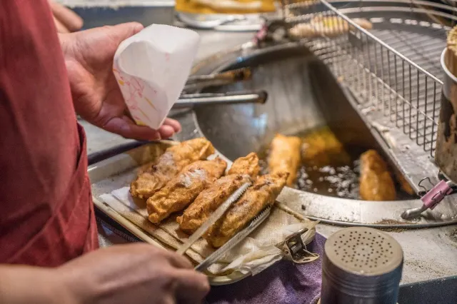 顏記深海旗魚串攤位,剛起鍋的旗魚串正在瀝油撒胡椒粉