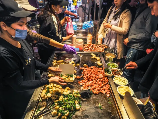 花園夜市紅妃香腸大腸攤位前的排隊人潮與鐵板