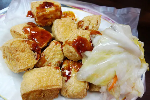 里長伯臭豆腐的炸臭豆腐淋上醬汁並附台式泡菜