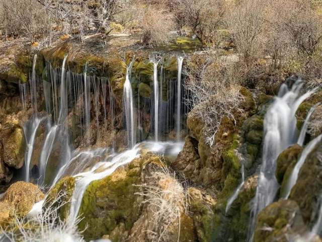A wide waterfall cascading through the forest in Jiuzhaigou