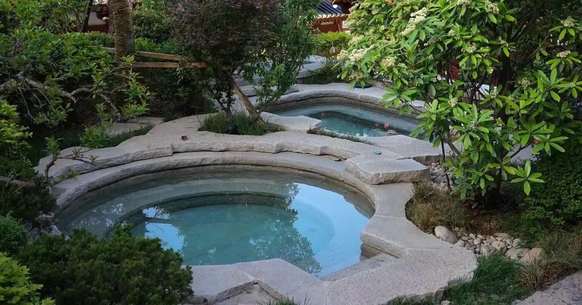 Die Thermal-Außenbecken von Huaqing Yutang, umgeben von Gärten im traditionellen chinesischen Stil. 