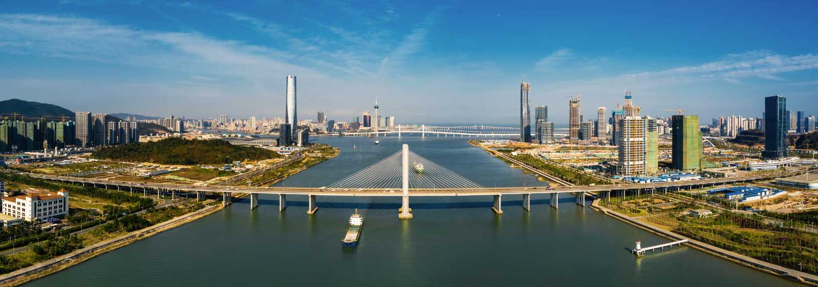 Panoramic aerial view of a modern city by the river with a cable-stayed bridge and skyscrapers