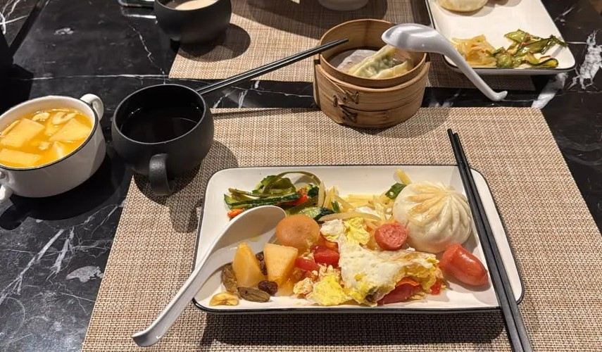 Chinese breakfast spread with dumplings, vegetables, fruit, and tea