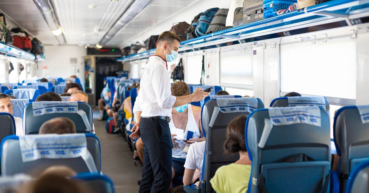 A train conductor checking tickets inside the train