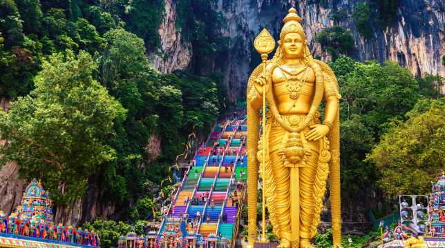 Golden Murugan statue and colourful stairs at Batu Caves, near Kuala Lumpur