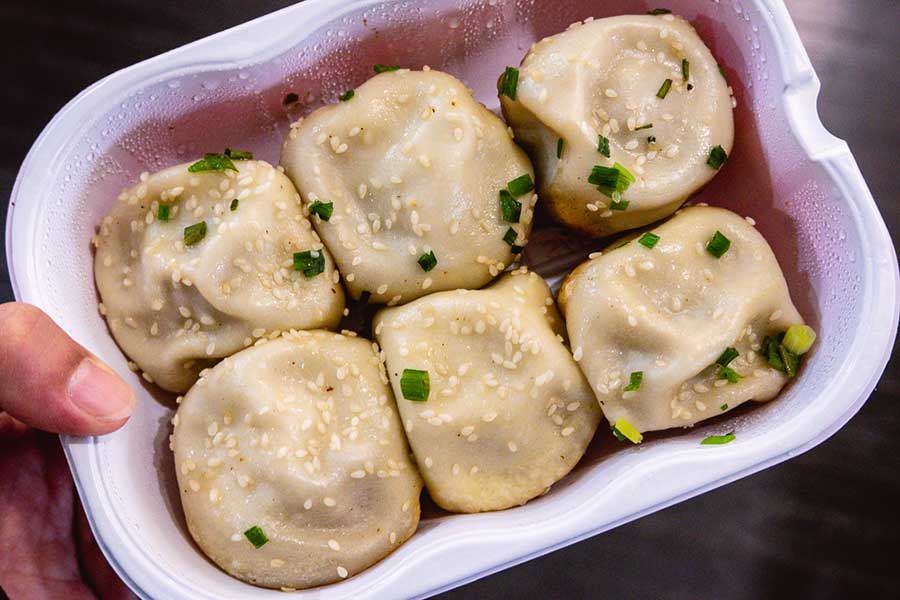 Pan-fried buns, shengjian bao, sprinkled with sesame seeds and chopped green onions