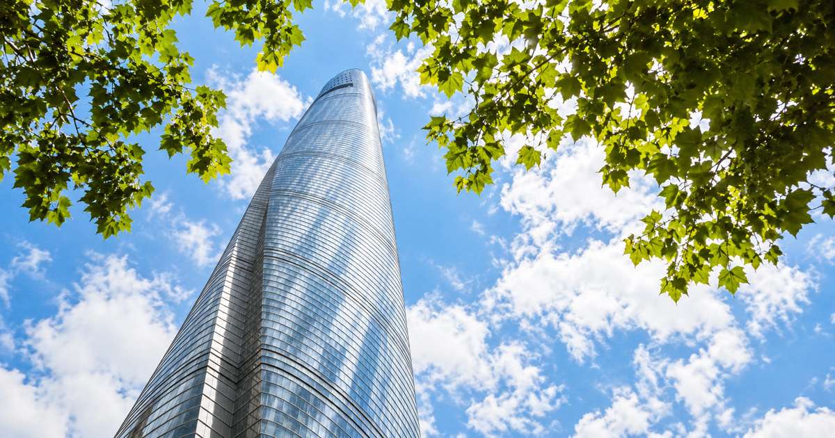 Fachada da Torre de Xangai vista do nível da rua entre árvores de Lujiazui