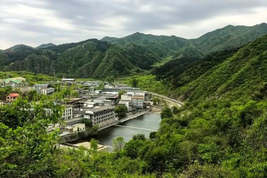 Mountain village beside a river surrounded by lush green hills