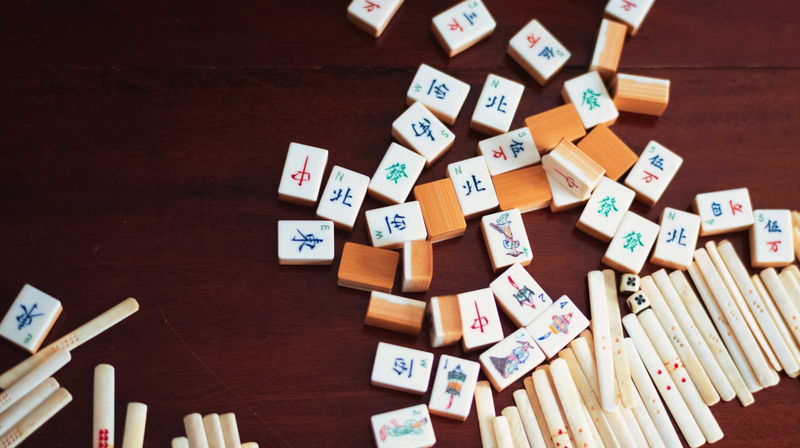 Fichas de mahjong tradicionales chinas dispersas sobre una mesa de madera oscura