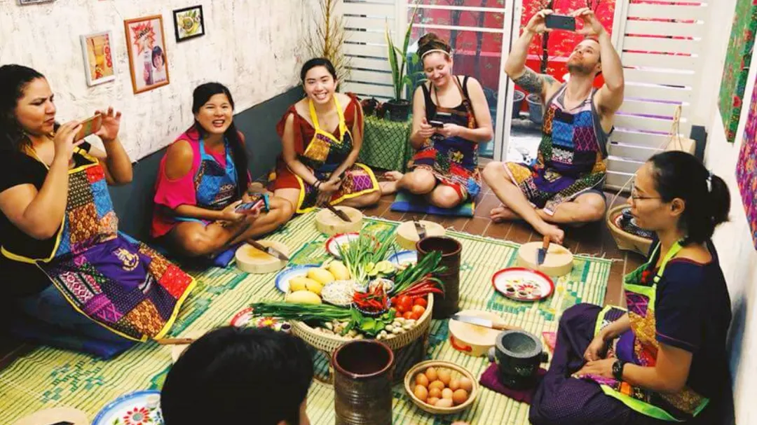Group of ladies learning how to cook traditional Thai dishes and having a conversation around the table