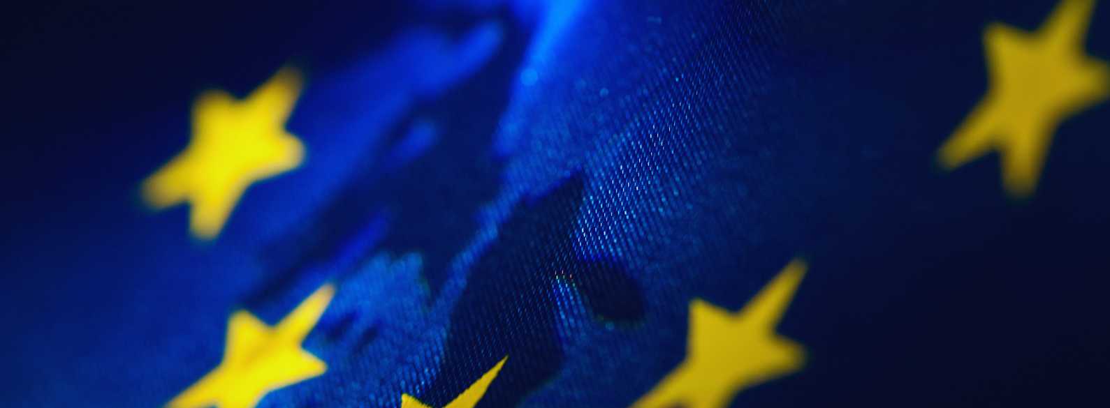 Detalle de la bandera de la Unión Europea ondeando con estrellas doradas sobre fondo azul