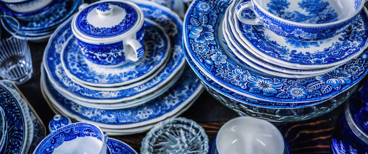 Blue and white porcelain tableware stacked with decorated plates, cups, and bowls