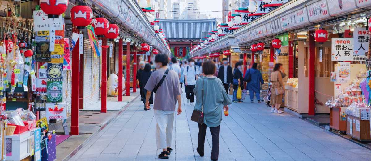 Rue traditionnelle japonaise ornée de lanternes rouges et bordée de boutiques locales au cœur d'un marché touristique animé