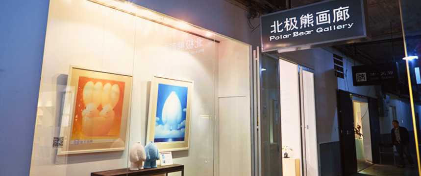 An art gallery entrance at night, featuring an illuminated window display and signage in Chinese and English.