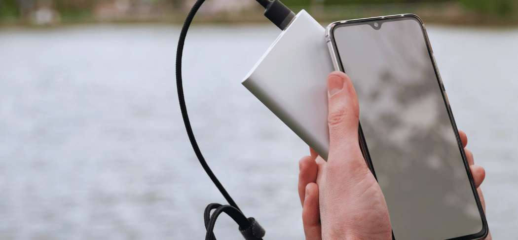 Une personne rechargeant son téléphone portable avec une batterie externe lors d'un voyage.