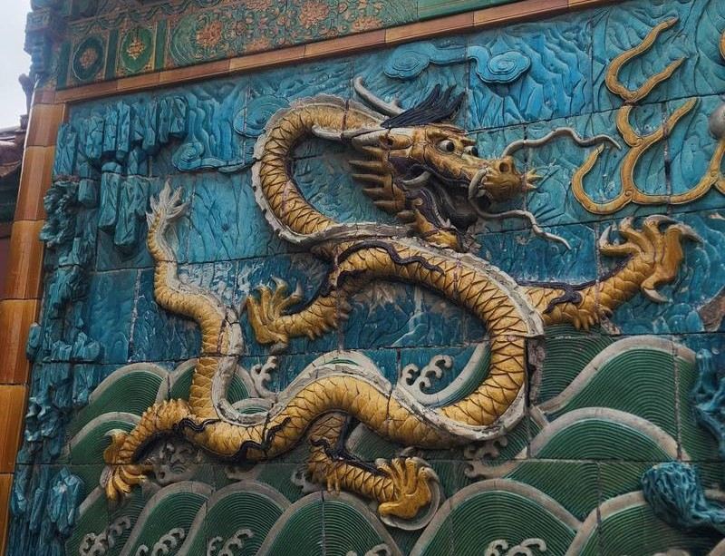 Ornate Chinese dragon relief on a blue ceramic wall