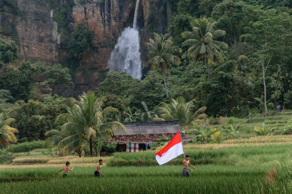 boys running around the village with an indonesian flag