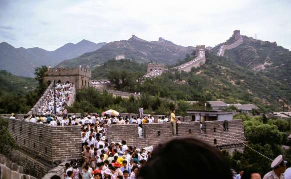 Gran Muralla China llena de turistas en un tramo concurrido con torres de vigilancia y montañas al fondo.