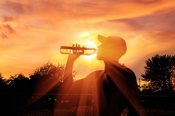 Guy drinking water because it is really hot