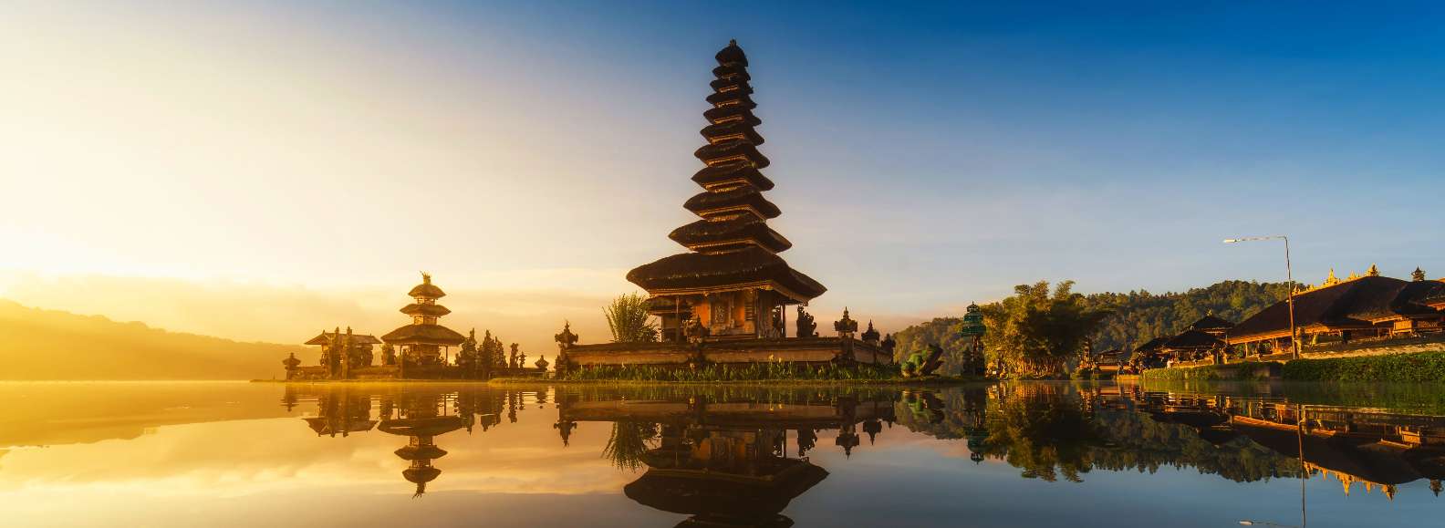 Templo balinés junto al agua al amanecer combinado con pasaportes españoles sobre un mapa antiguo, evocando viajes internacionales